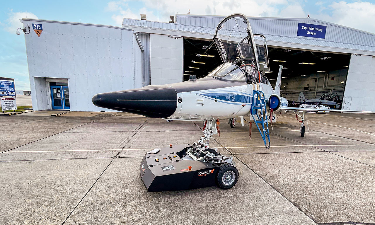 TowFLEXX TF4 Milspec electric tug towing a NASA T-38 Talon jet on an airstrip, highlighting advanced aerospace ground handling and collaboration between military technology and space exploration.