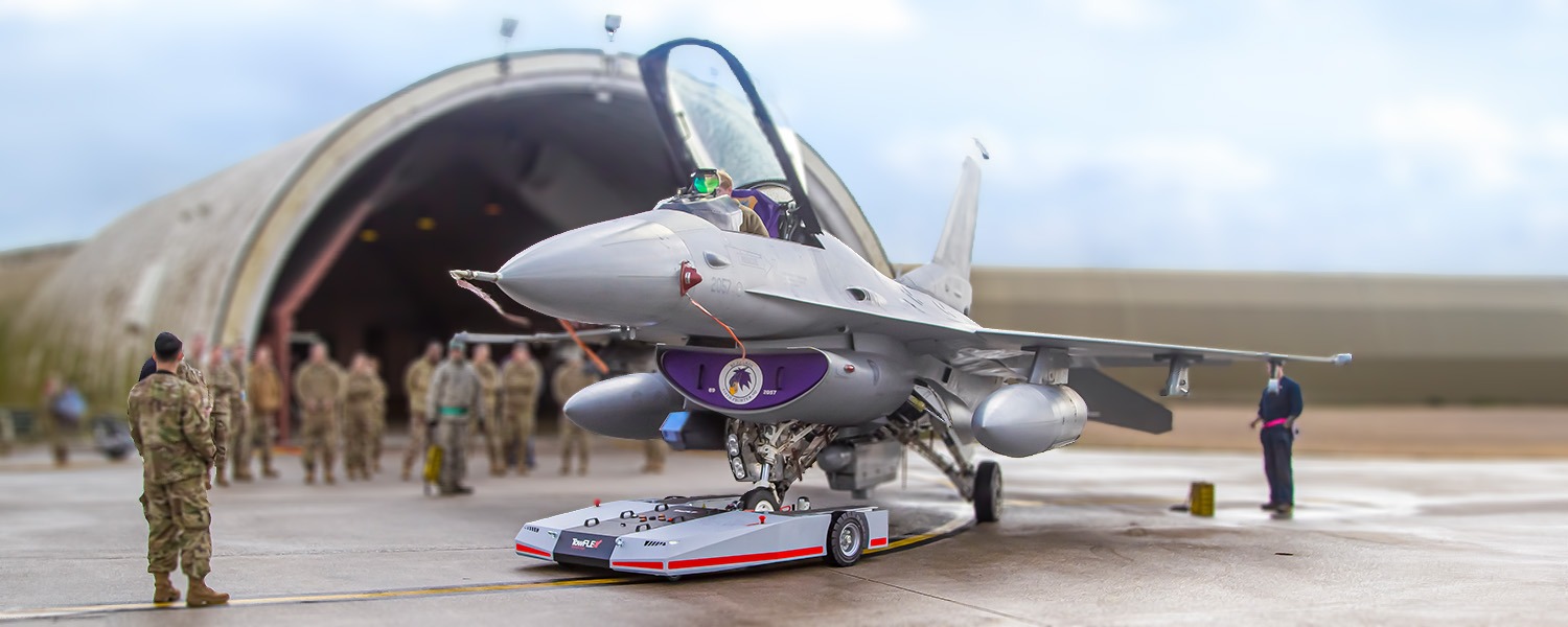 TowFLEXX TF5 MilSpec engaged in a training session with a USAF F-16 jet at Aviano Air Force Base in Italy, showcasing its interoperability and efficiency in aviation ground support.